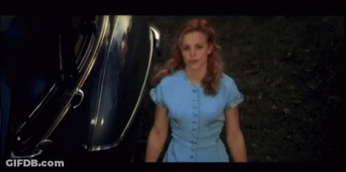 A Woman In A Blue Dress Is Standing In Front Of A Silver Car GIF