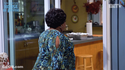 A Woman In A Blue Dress Is Standing In Front Of A Sliding Glass Door That Says House Of Payne GIF