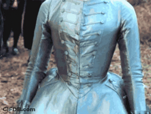 A Woman In A Blue Dress Is Standing In The Dirt GIF