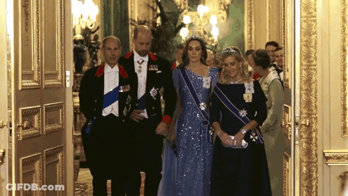 A Woman In A Blue Dress Is Standing Next To A Man In A Tuxedo And A Woman In A Black Dress GIF