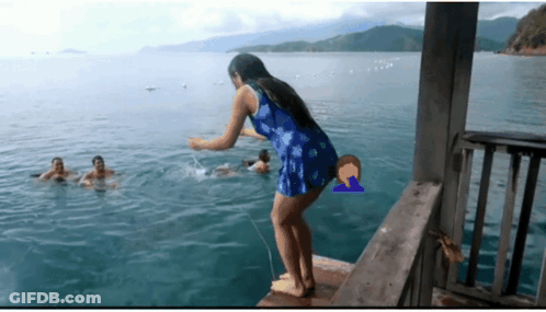 A Woman In A Blue Dress Is Standing On A Dock In The Ocean GIF