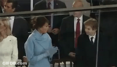 A Woman In A Blue Dress Is Talking To A Young Boy In A Suit And Tie . GIF