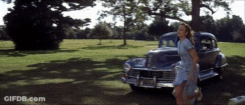 A Woman In A Blue Dress Is Walking In Front Of A Car With A License Plate That Says Jcj - 88 GIF