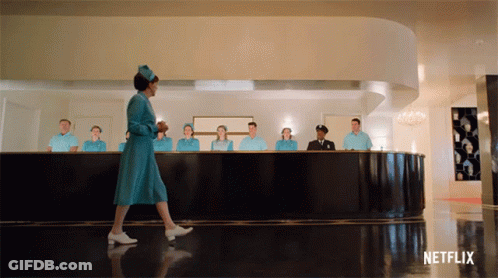A Woman In A Blue Dress Is Walking In Front Of A Netflix Ad GIF