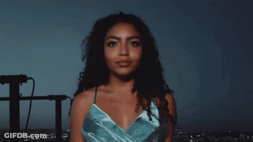 A Woman In A Blue Dress Looks At The Camera GIF