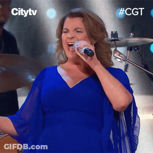 A Woman In A Blue Dress Sings Into A Microphone GIF