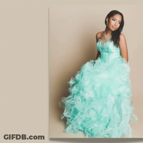 A Woman In A Blue Dress Stands In Front Of A Banner That Says Glam GIF
