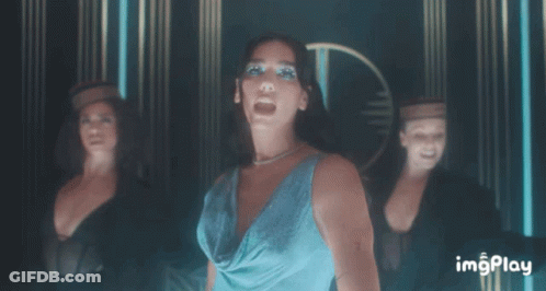 A Woman In A Blue Dress Stands In Front Of A Group Of Dancers With Imgplay Written On The Bottom Right GIF