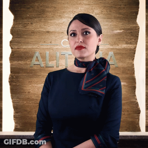 A Woman In A Blue Dress Stands In Front Of A Sign That Says Alit GIF
