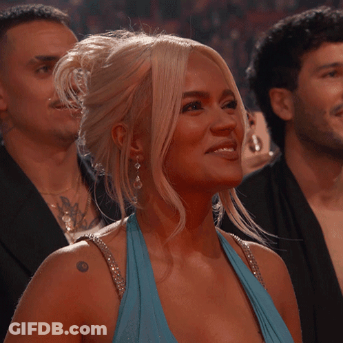 A Woman In A Blue Dress With A Tattoo On Her Shoulder Smiles GIF