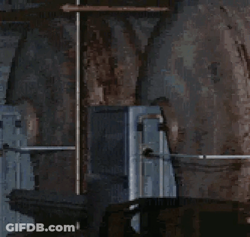 A Woman In A Blue Dress With A White Collar Is Standing In A Dark Room . GIF
