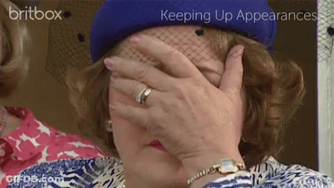 A Woman In A Blue Hat Covering Her Face With Her Hand GIF