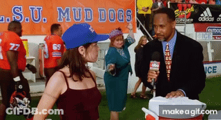 A Woman In A Blue Hat Is Dancing In Front Of A Sign That Says Mud Dogs GIF