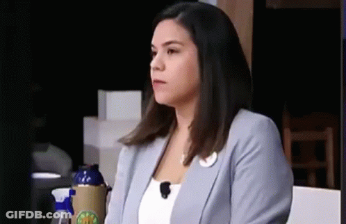A Woman In A Blue Jacket Is Sitting At A Table With A Microphone On Her Head . GIF