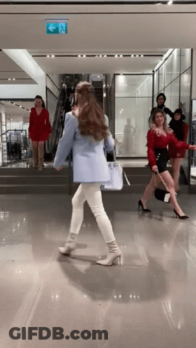 A Woman In A Blue Jacket Is Walking Down Stairs In A Store GIF