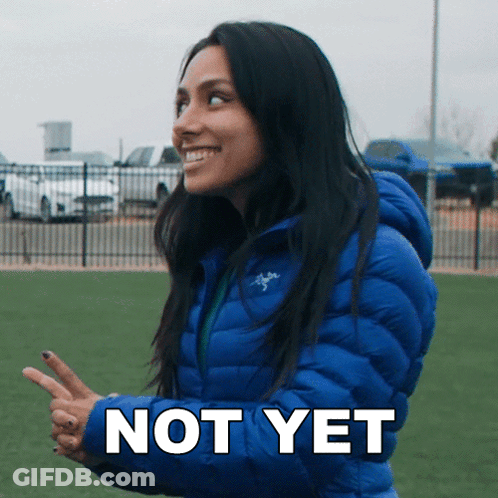 A Woman In A Blue Jacket Says " Not Yet " In White Letters GIF