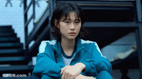 A Woman In A Blue Jacket Sits On Stairs GIF
