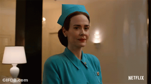 A Woman In A Blue Nurse 'S Uniform With A Netflix Logo Behind Her GIF