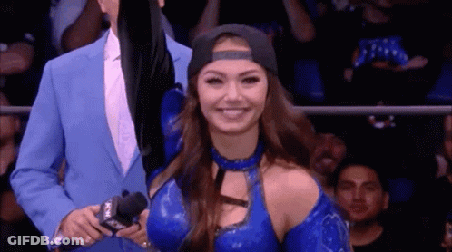 A Woman In A Blue Outfit Is Smiling While Standing Next To A Man In A Blue Suit . GIF
