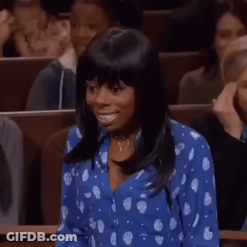 A Woman In A Blue Polka Dot Shirt Is Smiling In A Courtroom While Sitting In A Courtroom . GIF