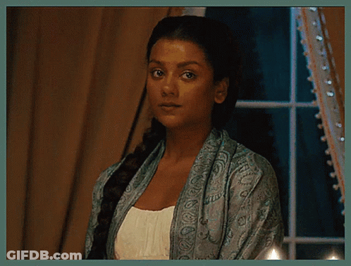 A Woman In A Blue Scarf Is Standing In Front Of A Window . GIF