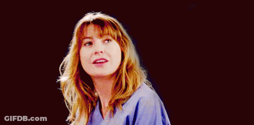 A Woman In A Blue Scrub Is Smiling And Looking At The Camera On A Black Background . GIF