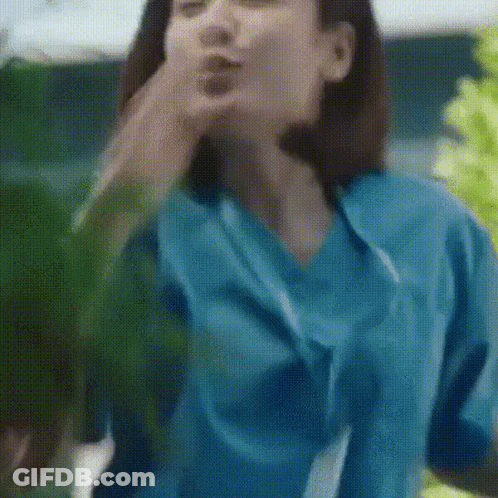 A Woman In A Blue Scrub Top Is Blowing A Kiss GIF