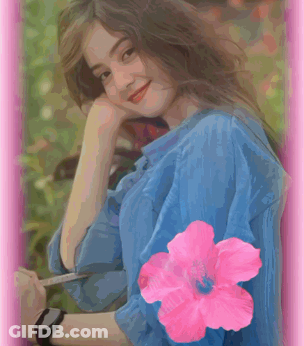 A Woman In A Blue Shirt Has A Pink Flower On Her Sleeve GIF