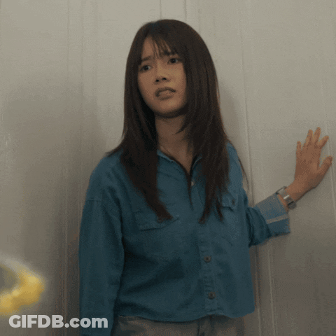 A Woman In A Blue Shirt Has Her Hand On The Wall GIF