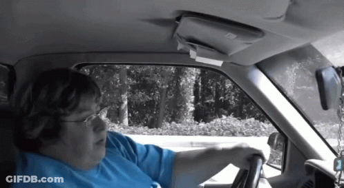 A Woman In A Blue Shirt Is Driving A Car With The Number 2 On The Steering Wheel GIF