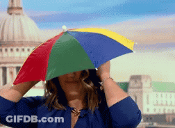 A Woman In A Blue Shirt Is Holding A Colorful Umbrella Over Her Face GIF