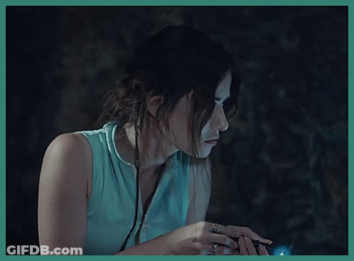 A Woman In A Blue Shirt Is Holding A Flashlight In Her Hand GIF
