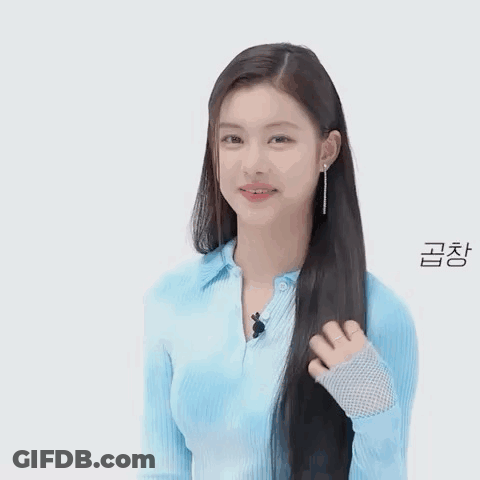 A Woman In A Blue Shirt Is Holding Her Hair And Smiling . GIF