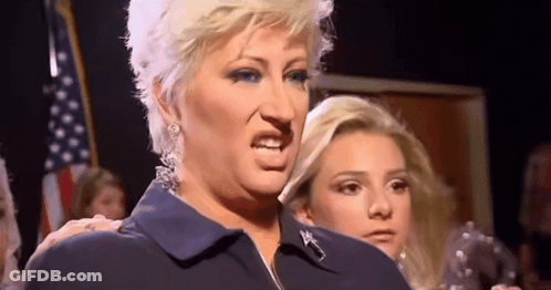 A Woman In A Blue Shirt Is Making A Funny Face In Front Of A Group Of People . GIF