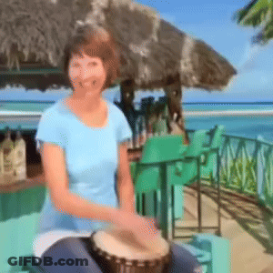 A Woman In A Blue Shirt Is Playing A Drum On The Beach GIF