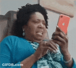 A Woman In A Blue Shirt Is Sitting In A Chair Looking At Her Phone . GIF
