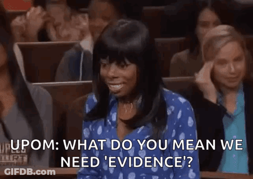 A Woman In A Blue Shirt Is Sitting In A Courtroom With A Crowd Of People . GIF