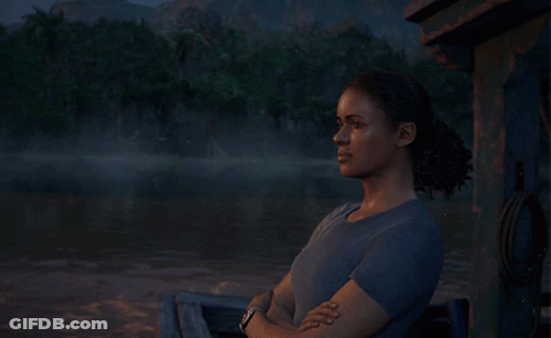 A Woman In A Blue Shirt Is Sitting In Front Of A Lake GIF
