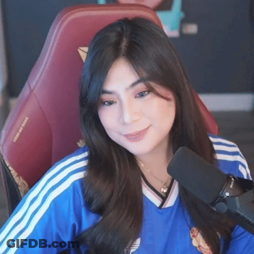 A Woman In A Blue Shirt Is Sitting In Front Of A Microphone . GIF