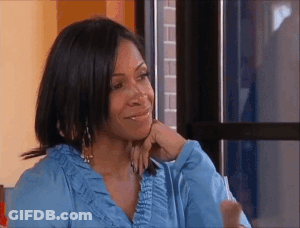 A Woman In A Blue Shirt Is Sitting In Front Of A Window . GIF