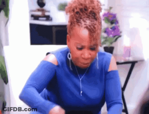 A Woman In A Blue Shirt Is Sitting On A Couch And Looking At Her Phone . GIF