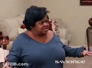 A Woman In A Blue Shirt Is Sitting On A Couch In A Living Room With The Words Savonce On The Bottom GIF