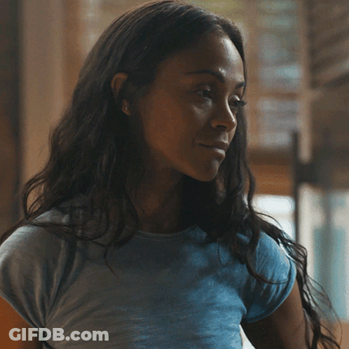 A Woman In A Blue Shirt Is Smiling And Looking At The Camera GIF