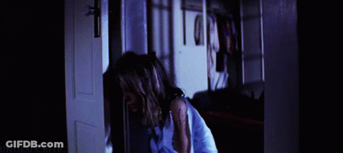 A Woman In A Blue Shirt Is Standing In A Doorway With The Words Undeadcritic On The Bottom Right GIF