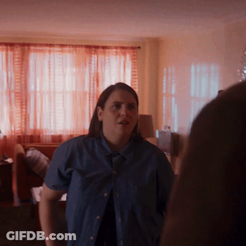 A Woman In A Blue Shirt Is Standing In A Room GIF