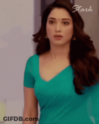 A Woman In A Blue Shirt Is Standing In Front Of A Sign That Says Stark . GIF