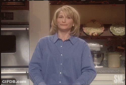 Woman In Blue Shirt Standing In Front Of SNL Logo GIF