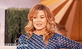 A Woman In A Blue Shirt Is Standing In Front Of A Window . GIF