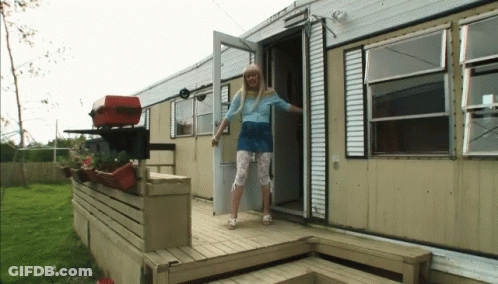 A Woman In A Blue Shirt Is Standing In The Doorway Of A Trailer GIF