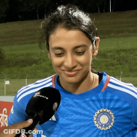 A Woman In A Blue Shirt Is Talking Into A Microphone While Smiling . GIF